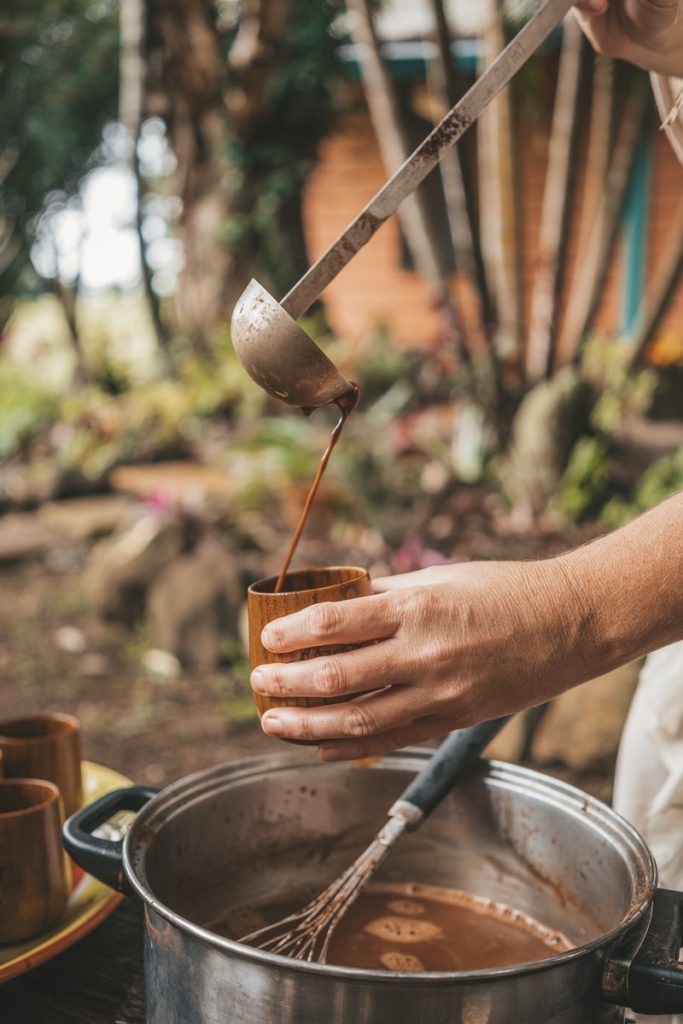 person holding brown wooden cup with silver spoon